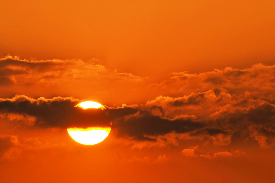 Photo | Sun behind a streak of clouds at sunset | UCLA